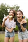 Teen asians girlfriends with candies having fun in the park — Stock Photo