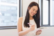 Молода жінка приймає нотатки в сучасному офісі — стокове фото
