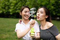 Милые азиатские подружки делают мыльные пузыри в парке
. — стоковое фото
