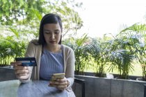 Молодая привлекательная азиатская женщина совершает сделку со смартфоном — стоковое фото