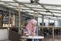 Jeune femme Jotting vers le bas quelques informations à un café — Photo de stock