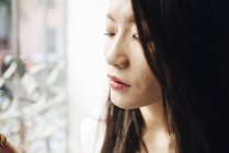 Attractive asian woman looking out of window — Stock Photo