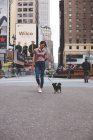 Beautiful Woman walking her dogs through the city with empire state behind. — Stock Photo