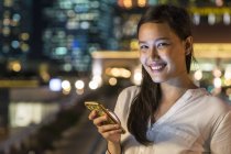 Jovem bela mulher asiática usando smartphone ao ar livre — Fotografia de Stock