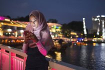 Девушка, использующая свой мобильный телефон на улице, ночное освещение, Испания — стоковое фото