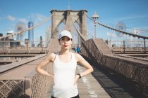 Jolie fille coureuse asiatique qui s'entraîne en plein air au Brooklyn Bridge avec Manhattan, New York en arrière-plan . — Photo de stock