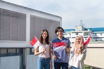 A group of friends posing with the Singapore Flags. — Stock Photo
