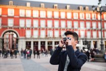 Jeune Chinois décontracté prenant des photos à la Plaza Mayor, Madrid, Espagne — Photo de stock