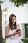 Прелестная азиатская девушка с телефоном на улице — стоковое фото