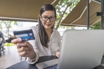 Young beautiful asian woman making transaction with laptop — Stock Photo