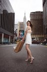 Une belle femme élégante marchant dans la rue et tenant des sacs à provisions avec Empire State Building . — Photo de stock