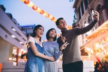Feliz asiático amigos celebrando chino año nuevo en ciudad y tomando selfie - foto de stock
