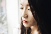 Приваблива азіатська жінка дивиться з вікна — стокове фото