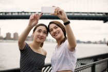 Mujeres tomando una selfie con el puente de Brooklyn en el fondo - foto de stock