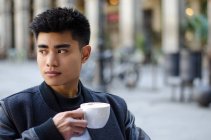 Portrait of a young asian man having a coffee in Barcelona, spain — Stock Photo