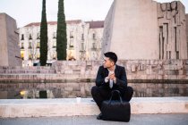 Усердный китайский бизнесмен, сидящий на улице и думающий о новых идеях для бизнеса, Испания — стоковое фото