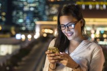 Junge schöne asiatische Frau mit Smartphone im Freien — Stockfoto