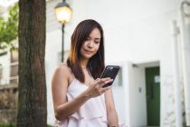 Bastante asiática chica con teléfono en la calle - foto de stock