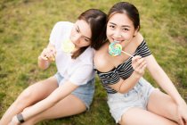 Teen asians girlfriends with candies having fun in the park — Stock Photo