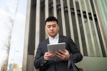 Homme d'affaires chinois avec une tablette dans la rue — Photo de stock