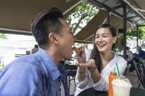 Young beautiful asian couple eating in cafe — Stock Photo