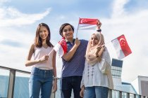 Un gruppo di amici in posa con le bandiere di Singapore. — Foto stock