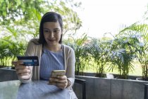 Young attractive asian woman making transaction with smartphone — Stock Photo