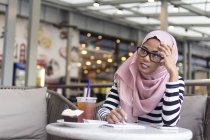 Young Woman Jotting Down Some Information At A Cafe — Stock Photo
