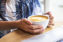 Abgeschnittenes Bild einer Frau, die eine Tasse Kaffee hochhält — Stockfoto