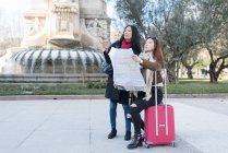 Asian women doing tourism in Madrid with map and suitcase — Stock Photo