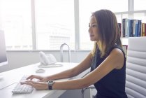 Jovem asiático mulher de negócios trabalhando com computador no escritório moderno — Fotografia de Stock