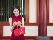 Chinese woman holding oranges and looking down — Stock Photo