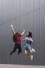 Jovem asiático faculdade estudantes salto e posando contra cinza parede — Fotografia de Stock