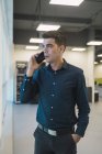 Молодой азиатский бизнесмен разговаривает на смартфоне в современном офисе — стоковое фото