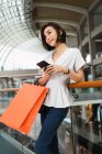 Jovem bela mulher asiática com saco de compras e smartphone — Fotografia de Stock