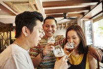 Happy young asian friends together in bar with beer — Stock Photo