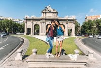Japanese and Chinese female travellers standing and posing at Puerta de Alcala in Madrid, Spain. — Stock Photo