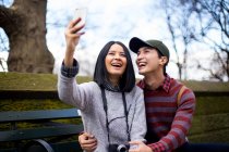 Joven asiático pareja de turistas tomando selfie en central park, Nueva York, EE.UU. - foto de stock