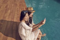 Attractive young asian women relaxing near pool — Stock Photo