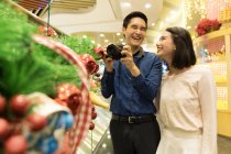 Jeune attrayant asiatique couple ensemble shopping dans le centre commercial à noël — Photo de stock