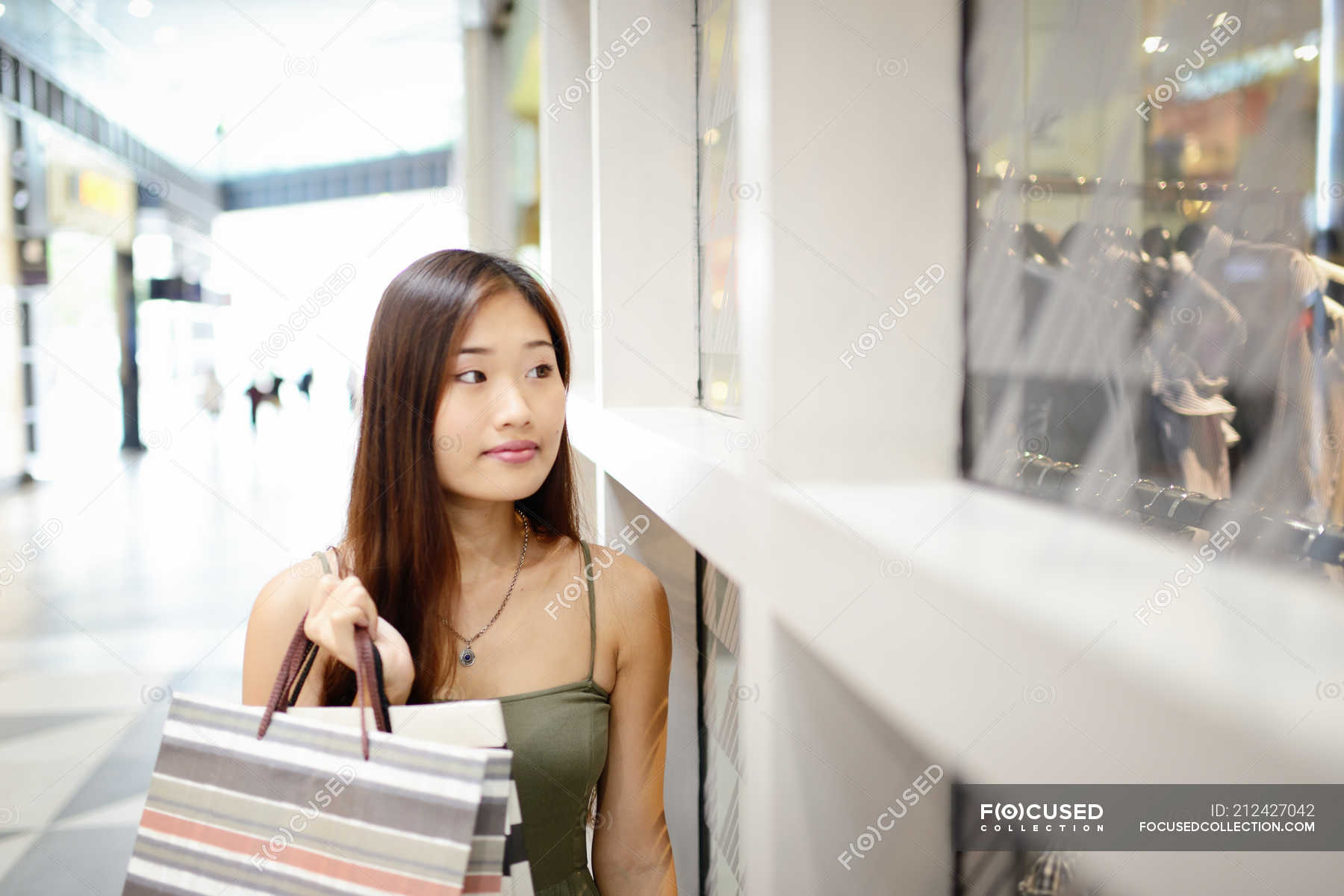 Gorgeous millennial Asian woman in trendy clothes is on the phone with  someone while shopping alone at the luxury shopping center. urban lifestyle  con Stock Photo - Alamy