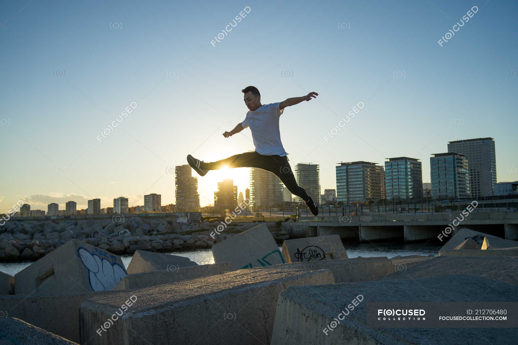 Young asian man jumping on blocks at sunset — white, street Stock
