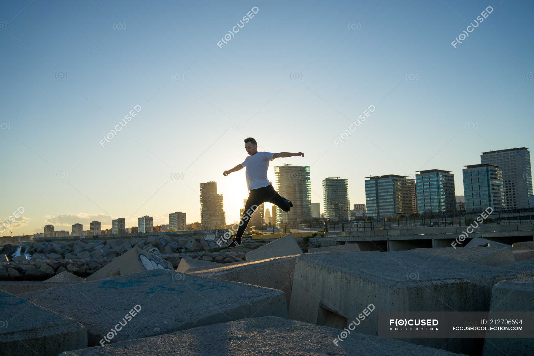 Young asian man jumping on blocks at sunset — outdoors, millennial