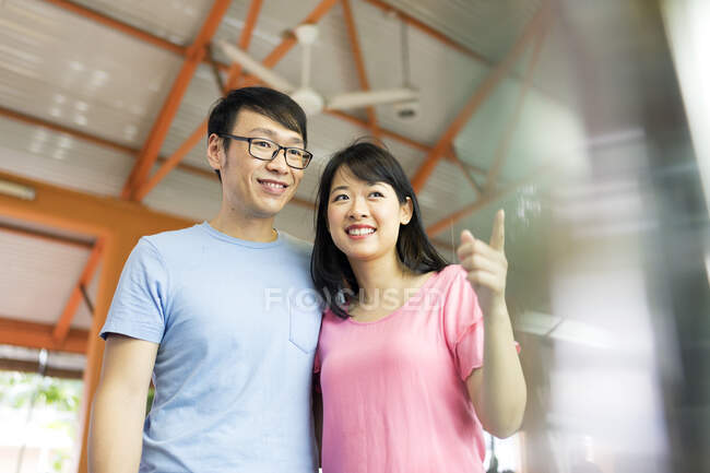 RELEASES Happy asian couple hugging together, woman pointing — Stock Photo