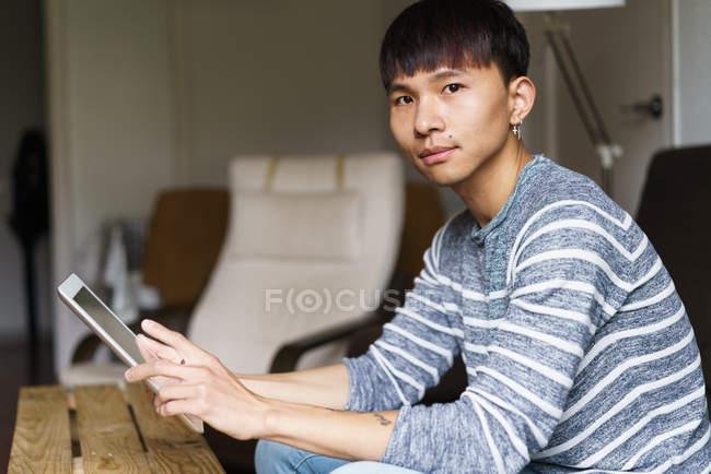 Jeune homme regardant l'appareil photo avec la tablette dans les mains — Photo de stock