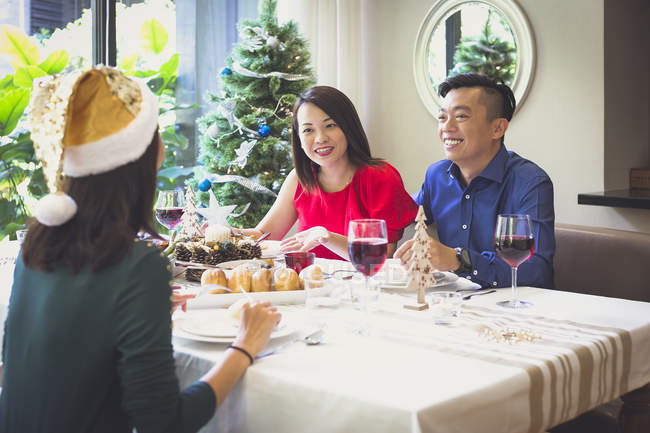 Singaporean couple enjoys a festive dinner with a friend in their beautiful house during Christmas holidays. — Stock Photo