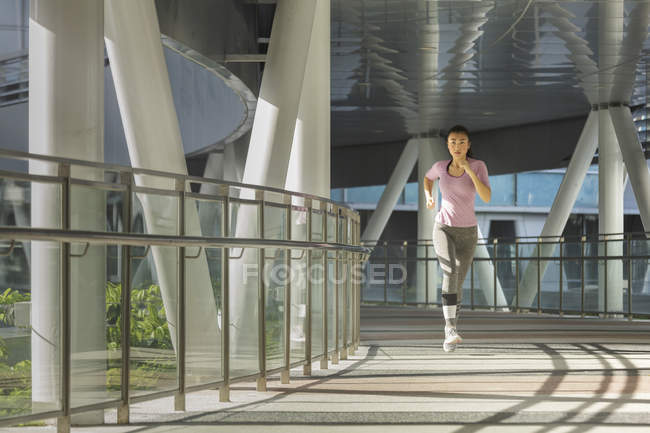 Ранним утром в Сингапуре бегает молодая азиатка. Она проходит секцию стальной и стеклянной архитектуры . — стоковое фото