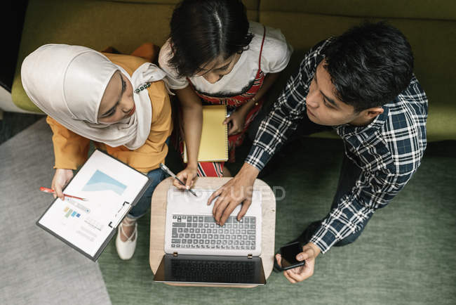 Vista superior de jovens empresários multiculturais que trabalham com laptop no escritório moderno — Fotografia de Stock