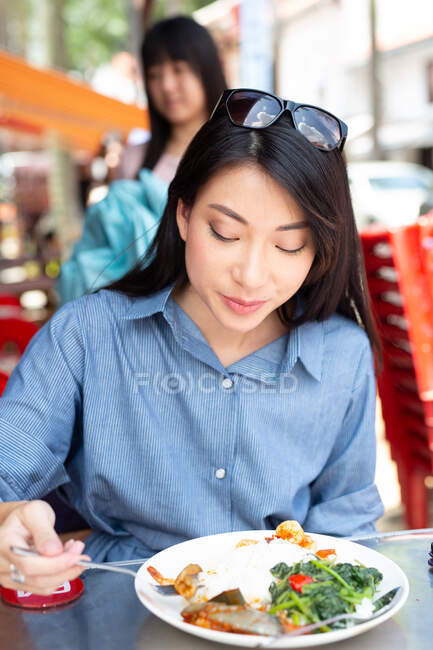 Attractive asian woman eating food at street cafe — Stock Photo