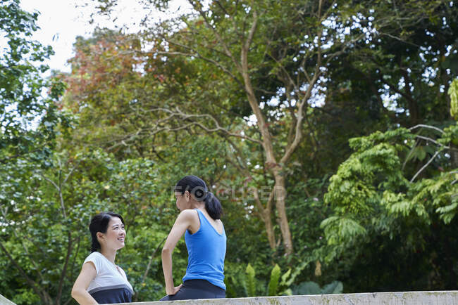 Dos mujeres poniéndose al día antes de su entrenamiento en Botanic Gardens, Singapur - foto de stock